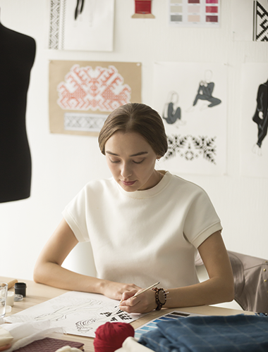 serious millennial dressmaker drawing new capsule collection